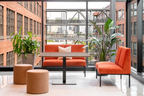 Modern office lounge with orange seating and plants.