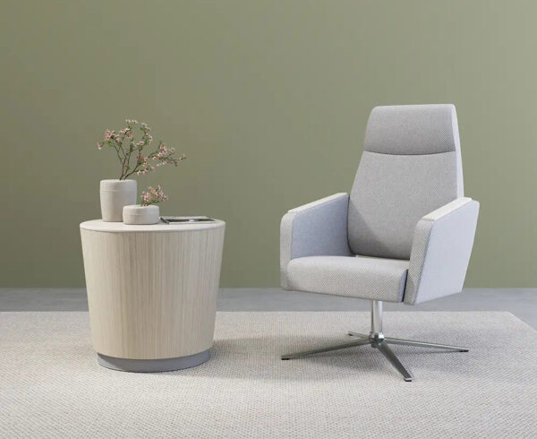 Modern chair beside table with vase and flowers.