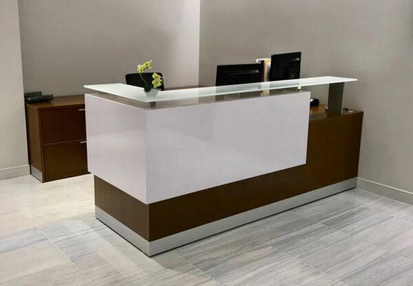 Modern reception desk with computers and flowers.