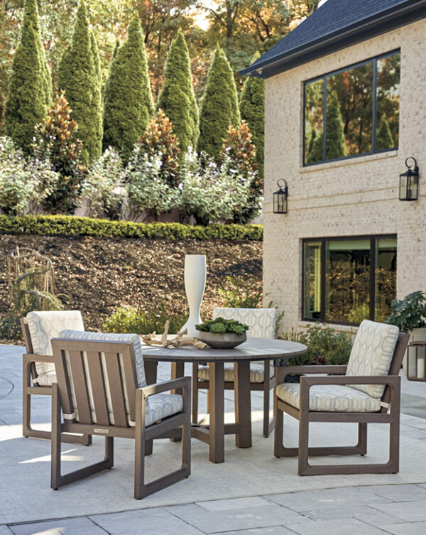 Outdoor patio furniture on stone terrace with greenery.