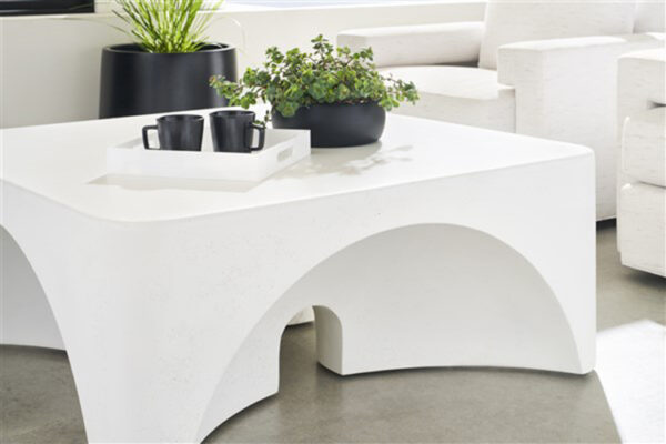 Modern white coffee table with plants and mugs.