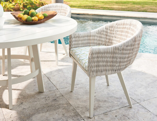 Outdoor wicker chairs by poolside table with lemons.