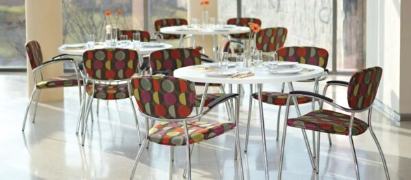 Colorful dining chairs around white tables in modern setting.