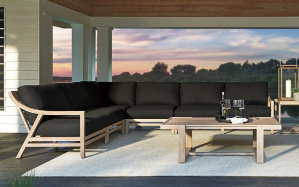 Outdoor patio with black sectional and wooden table.